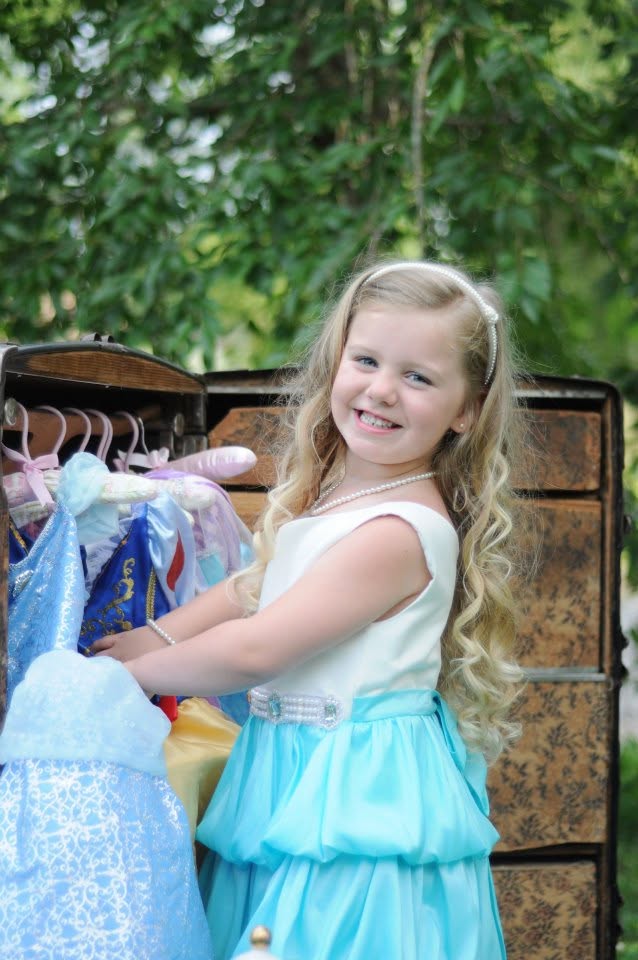 A little girl choosing from a wardrobe of princess dresses